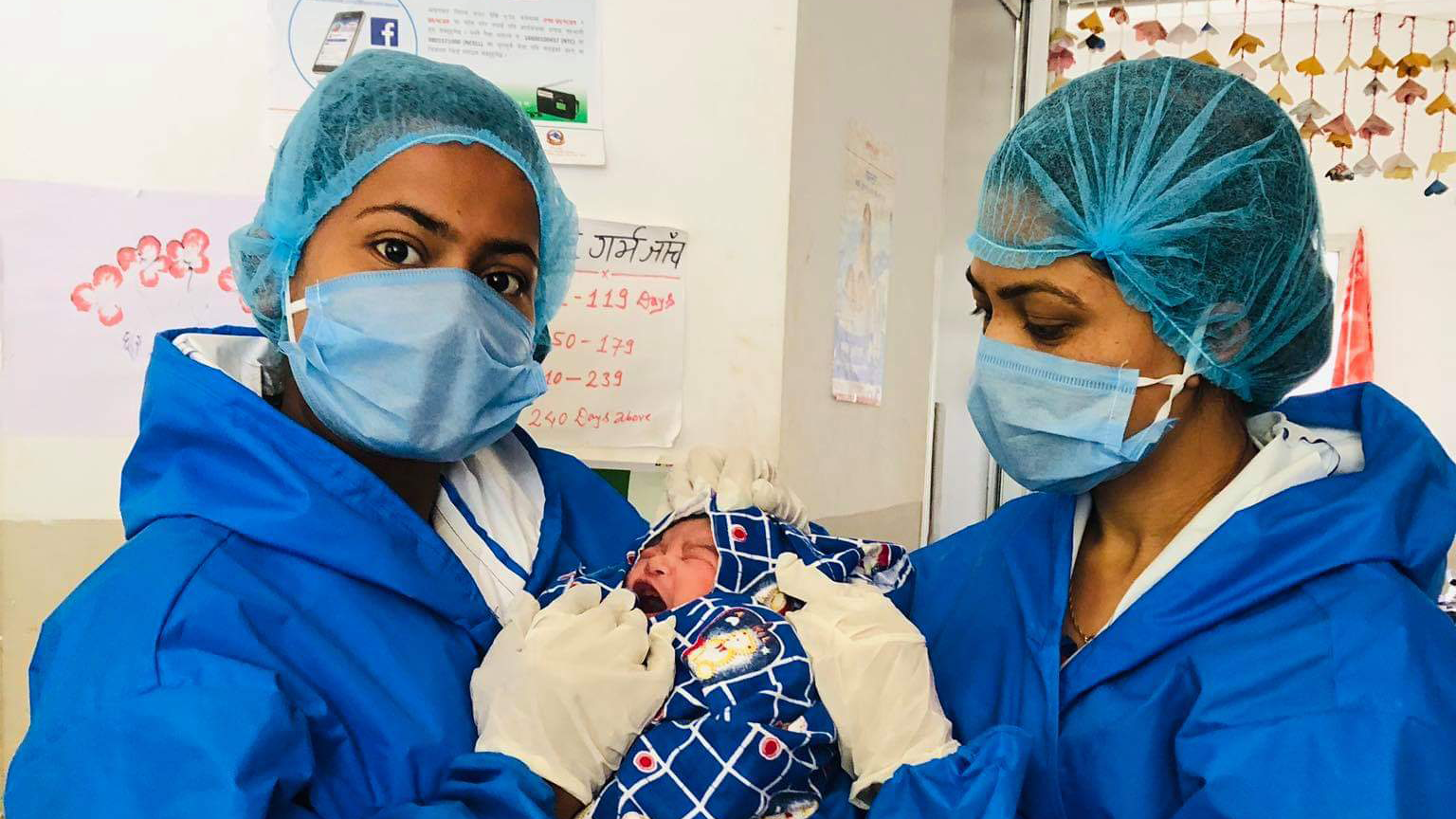 Credit: One Heart Worldwide. Description: Photo shows two nursing staff with newborn after delivery.